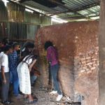 image of a group of people looking inside a large brick kiln